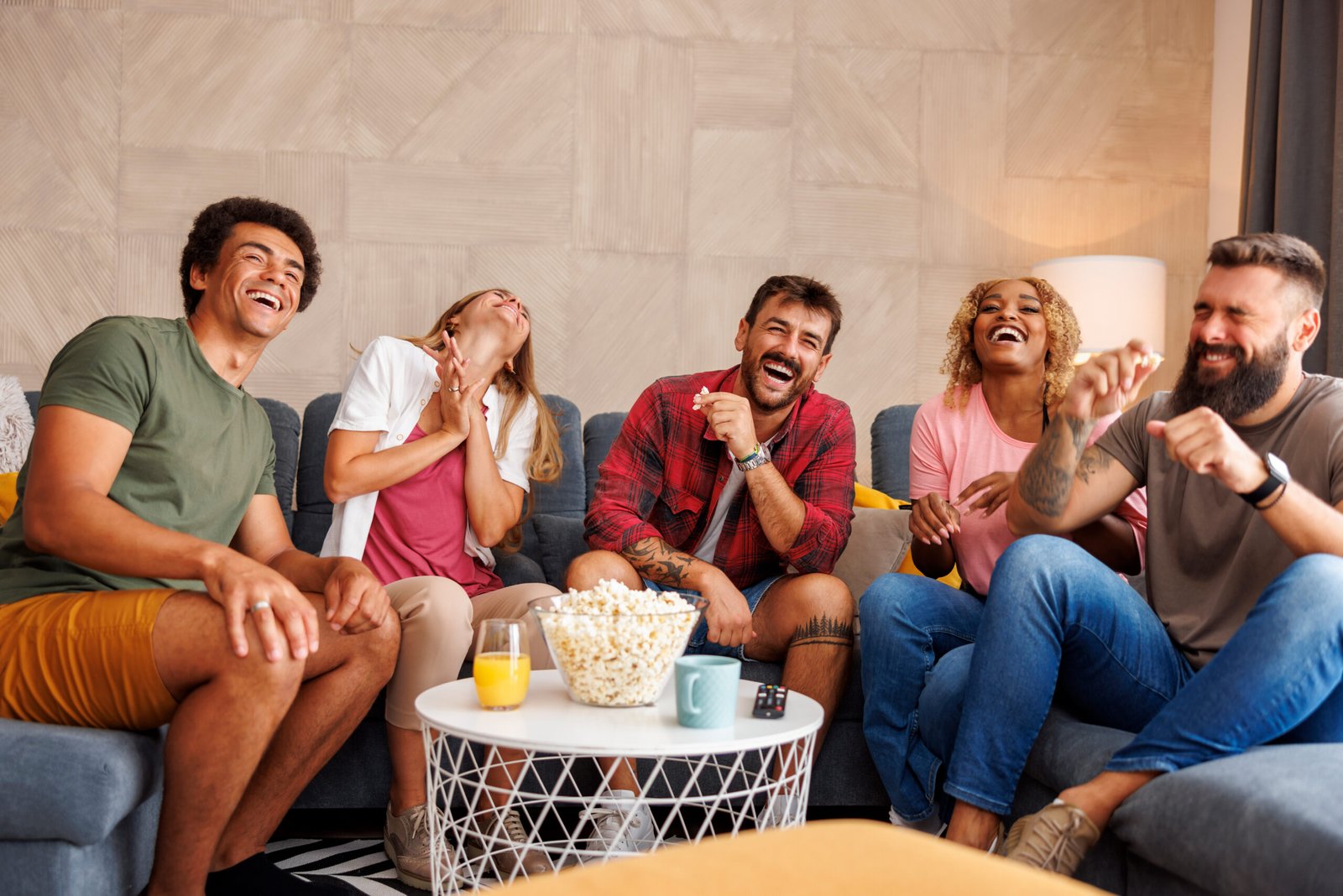 Friends laughing while watching TV at home